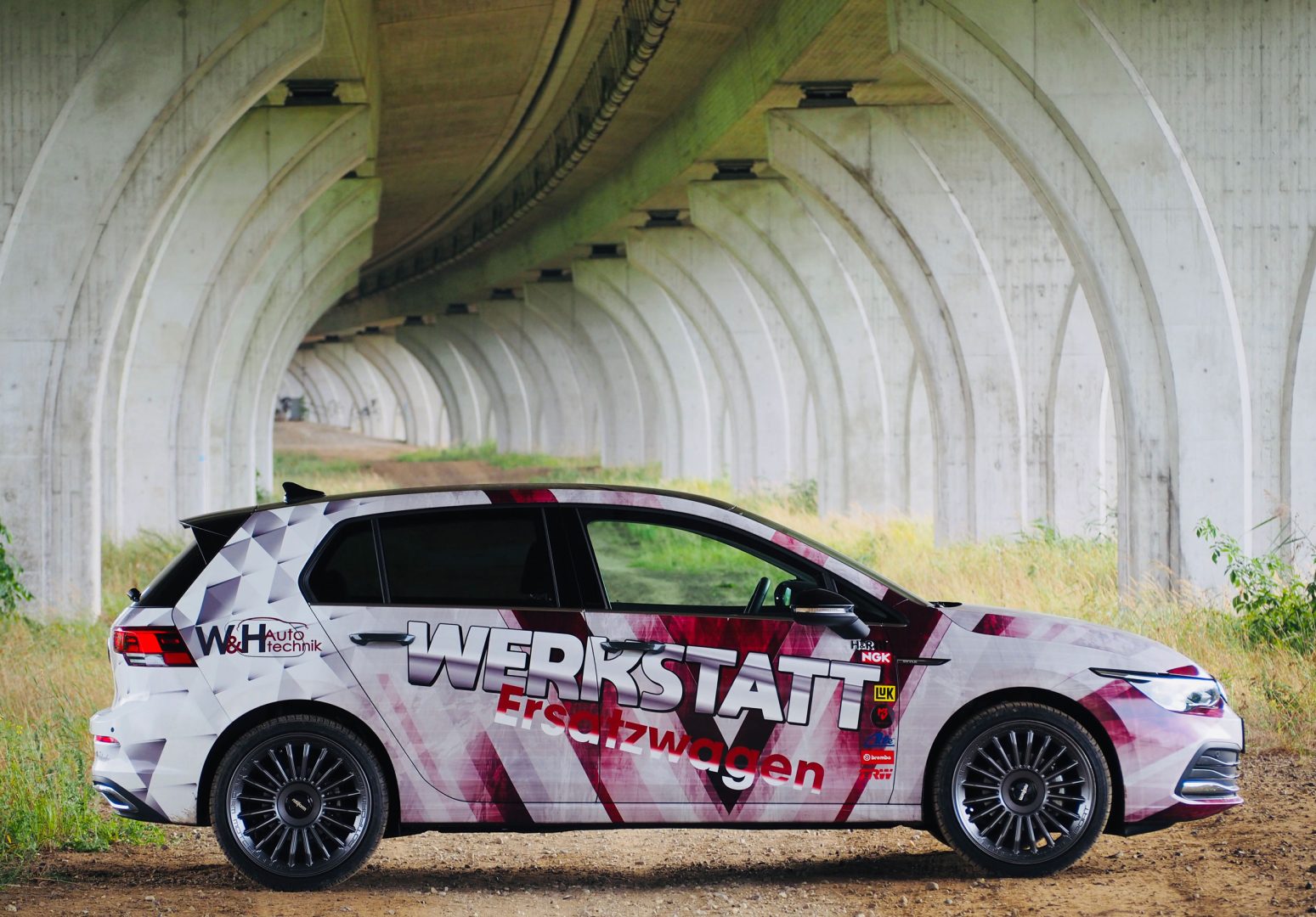 Gebrandeter W&H Autotechnik Werkstattersatzwagen unter einer Betonbrücke